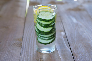 Glass of freshness water with cucumber on wooden background