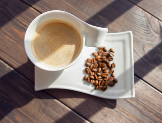 white mug of coffee with grains on a wooden background