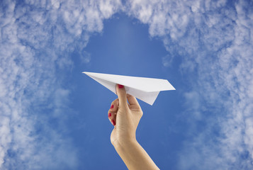 Hand holding paper plane on sky background