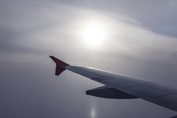 Naklejka premium Samolot leci nad morzem we mgle na tle tarczy słonecznej