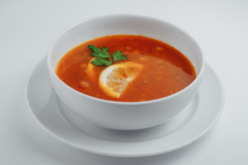 Solyanka with lemon and parsley in a white plate