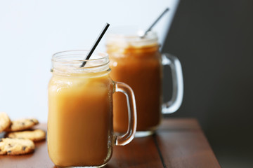 Iced coffee in glass jar with straw on brown wooden table