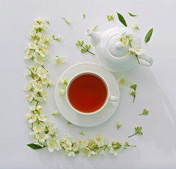 Cup of tea with jasmine flowers on white background