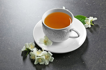 Cup of tea with jasmine flowers on color background