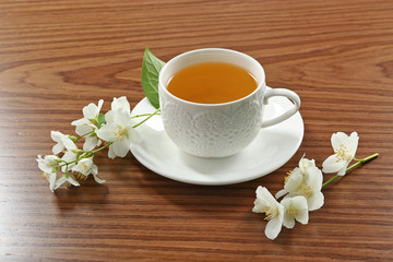 Obraz na płótnie Canvas Cup of tea with jasmine flowers on wooden background