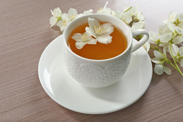 Cup of tea with jasmine flowers on wooden background