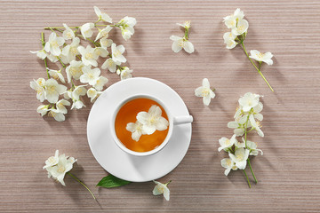 Cup of tea with jasmine flowers on wooden background
