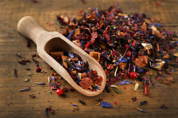 Dry tea leaves with spoon on wooden table