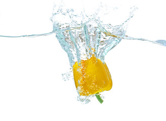Fresh yellow pepper falling in water on white background