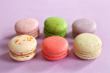 Colorful tasty macaroons in row on purple background