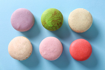 Colorful tasty macaroons in row on light blue background
