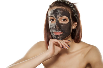 young woman with mud mask on her face