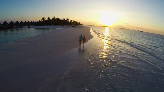 Couple on a tropical beach at Maldives - aerial view during sunset