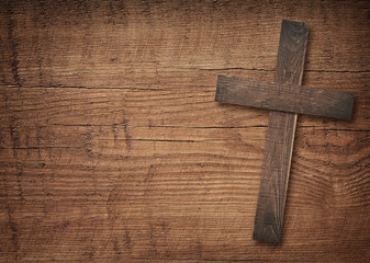 Wooden cross on brown old table top