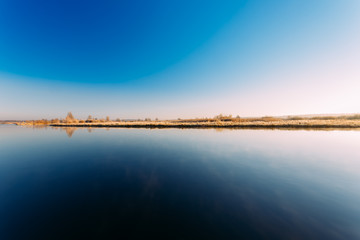 Panorama of sun rises over river. Autumn frost frozen river covered