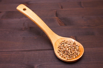 Wooden spoon with coriander seeds on a wooden table