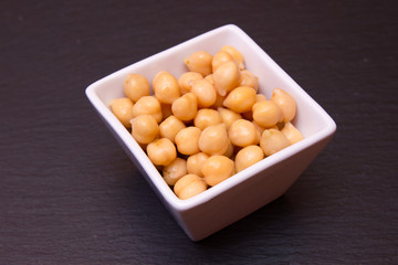 Boiled chickpeas on a square bowl on a slate floor