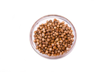 Coriander seeds on a bowl on a white background seen from above