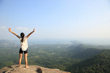 young freedom woman open arms on mountain peak