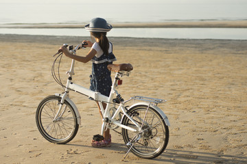 Little girl  with bicycle on the beach in the morning
