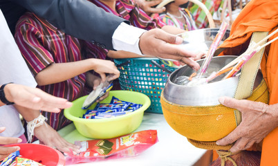 people give alms to a Buddhist Thai monk on morning
