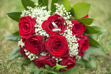 bridal bouquet of red roses on green grass, vintage filtered style
