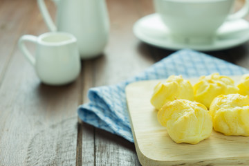 Close-up eclairs with custard cream and cup of coffee on wooden dish on old wooden wood table background texture 