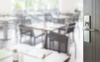 opened wooden door to set of table and chair in a restaurant