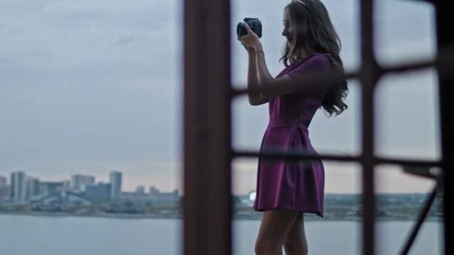 Attractive young woman fashion model in purple party dress photographs outdoor in front of skyline, close up