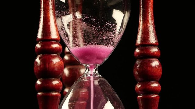 Sand goes from the top of the hour. Black. Slow motion. Close up