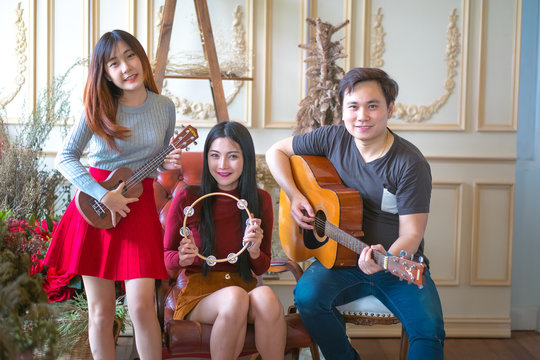 Three young Boy&girl friends having fun and smiling and Playing Guitar and instruments.