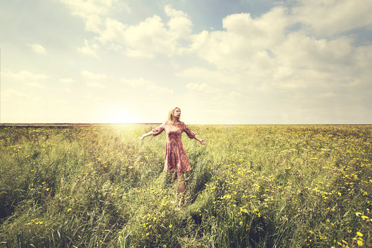 dreamy woman walking in nature illuminated by the sun