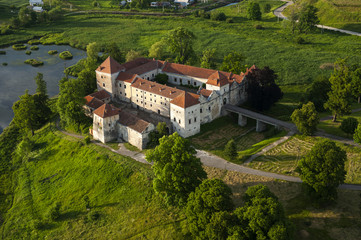 Fototapeta na wymiar Countryside aerial view on old castle with red roof over the lake