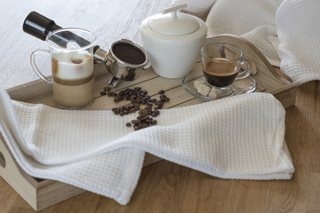 Fototapeta na wymiar Wooden tray with glass of latte macchiato, espresso, grouphead, coffee beans and brown sugar