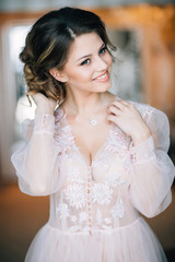 Naklejka premium girl in boudoir gown with a smile on his face corrects hairstyle