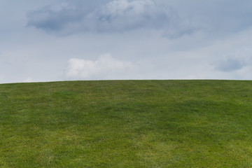 Green grass on the hill and cloudy sky