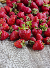 Fresh strawberry harvest scattered on rustic wooden table