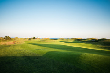 Beautiful golf course with sand traps and sea in the background at sunset