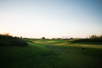 Beautiful golf course with palm trees on the background at sunset