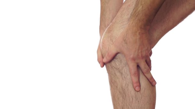 Closeup of an anonymous man isolated on a white background and rubbing his sore and painful leg knee joint.