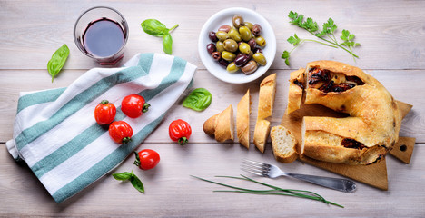 Fototapeta na wymiar Sun-dried tomato bread with olives, cherry tomatoes and red wine