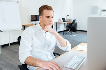 Thoughtful young businessman using computer at work