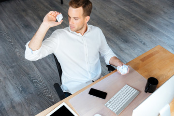 Serious businessman throwing crumpled paper and working in office