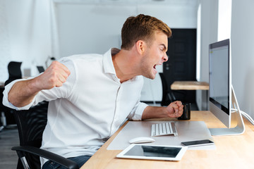 Aggressive furious businessman shouting and working with computer in office