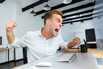Mad aggressive young businessman shouting in office