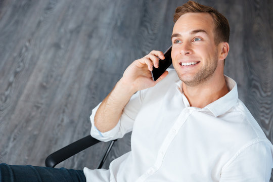 Smiling Young Businessman Talking On Mobile Phone In Office