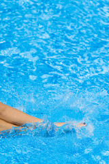Sexy women legs splashing in swimming pool