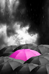 A single pink umbrella with dark stormy clouds