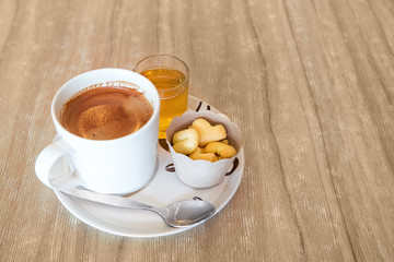 Coffee in white cup on disk with small cookies