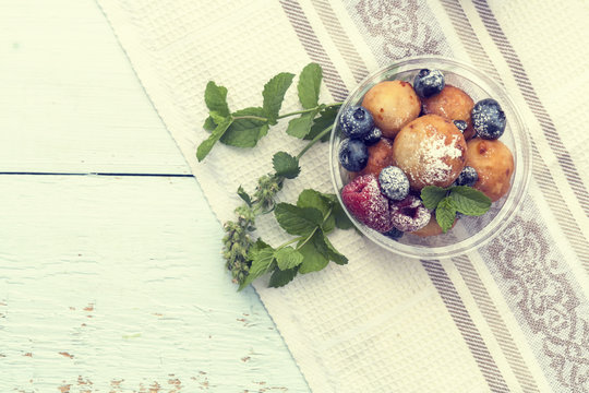 Breakfast, with cottage cheese balls with raspberry, blackberry and blueberry and mint on light table.  Toned and processing photos with soft selective focus. Shallow depth of field